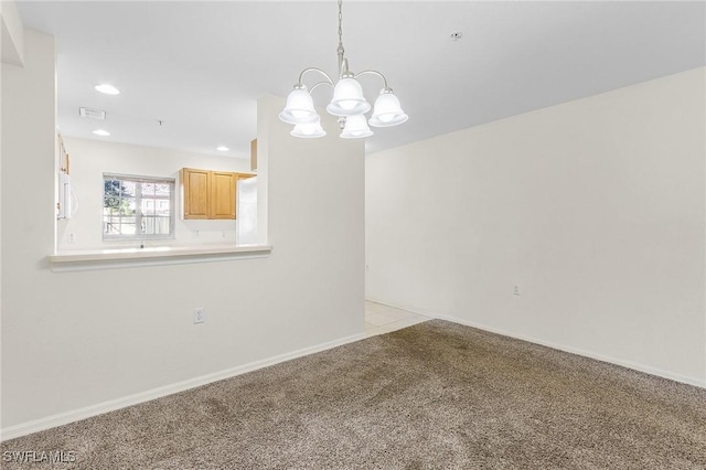 carpeted empty room featuring a chandelier