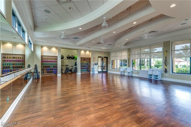 workout area with hardwood / wood-style floors, crown molding, ceiling fan, and a towering ceiling