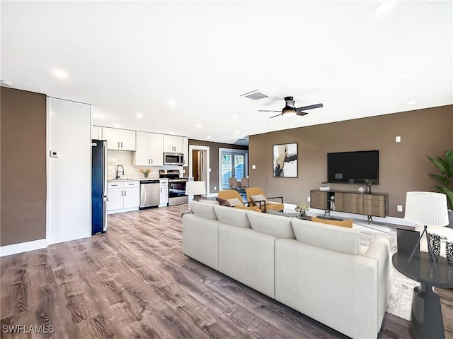 living room with ceiling fan, light wood-type flooring, and sink