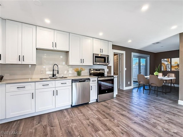 kitchen featuring white cabinetry, sink, stainless steel appliances, tasteful backsplash, and light hardwood / wood-style flooring