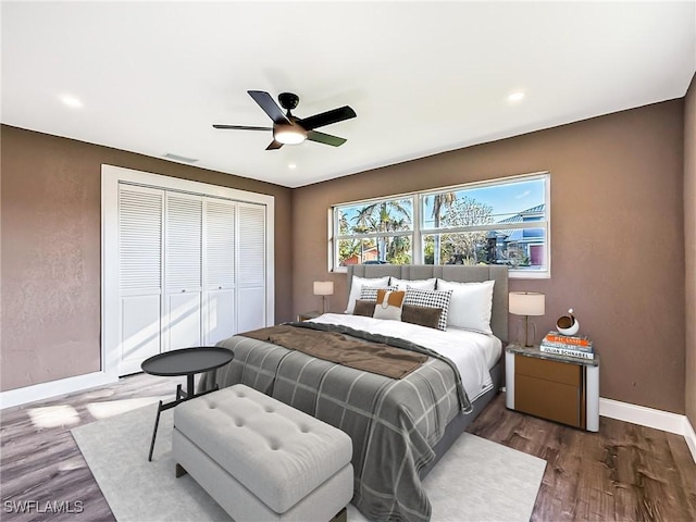 bedroom with ceiling fan, dark wood-type flooring, and a closet