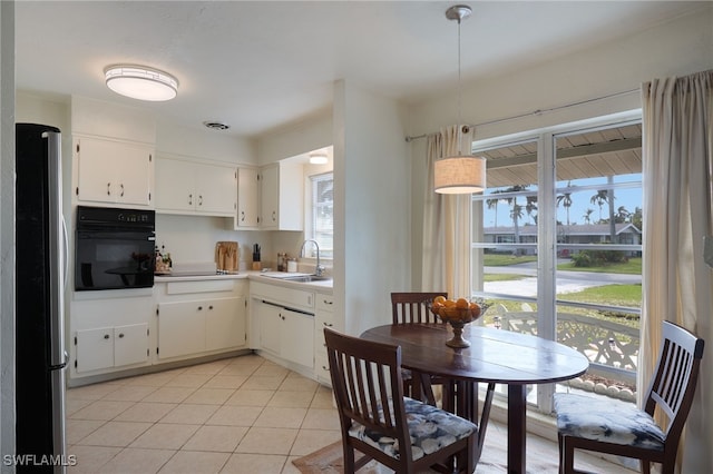 kitchen with white cabinetry, sink, light tile patterned floors, and black appliances