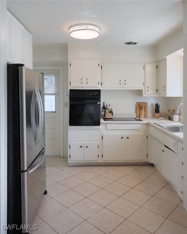 kitchen featuring light tile patterned flooring, sink, white cabinetry, and black appliances