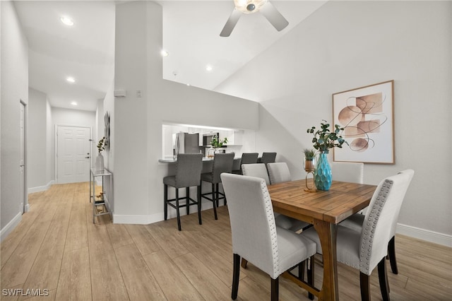 dining room featuring ceiling fan, light hardwood / wood-style flooring, and a high ceiling