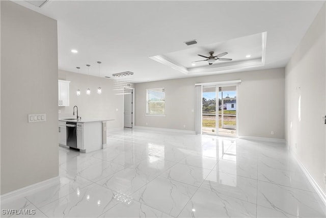 empty room featuring a raised ceiling, ceiling fan, and sink