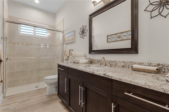 bathroom with hardwood / wood-style floors, vanity, an enclosed shower, and toilet