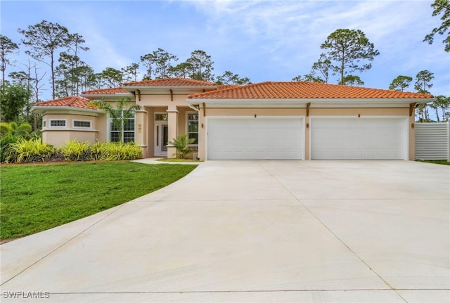 mediterranean / spanish home featuring a front yard and a garage