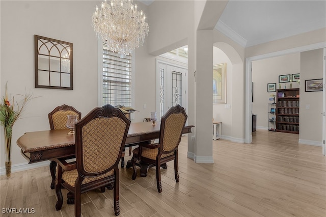 dining area with ornamental molding, light hardwood / wood-style flooring, and a notable chandelier