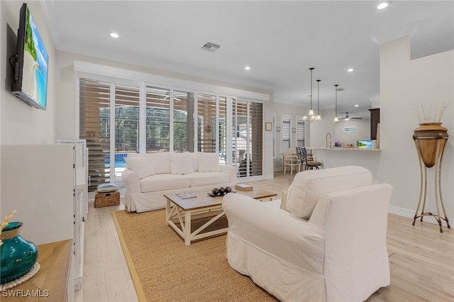 living room featuring ceiling fan, light hardwood / wood-style flooring, and crown molding