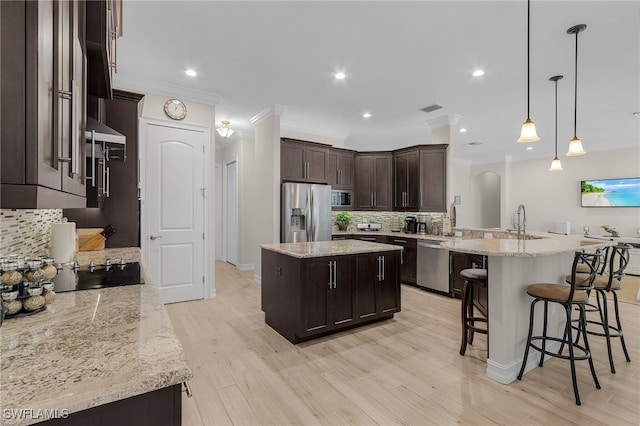 kitchen featuring pendant lighting, a center island, backsplash, kitchen peninsula, and stainless steel appliances