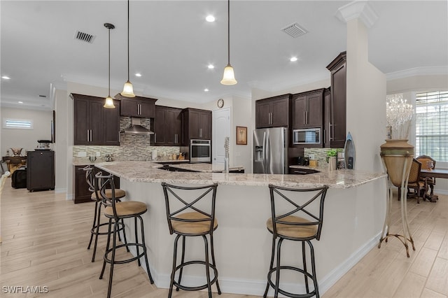 kitchen with pendant lighting, a breakfast bar, light stone countertops, stainless steel appliances, and extractor fan