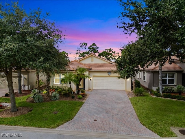 mediterranean / spanish house featuring a garage and a yard