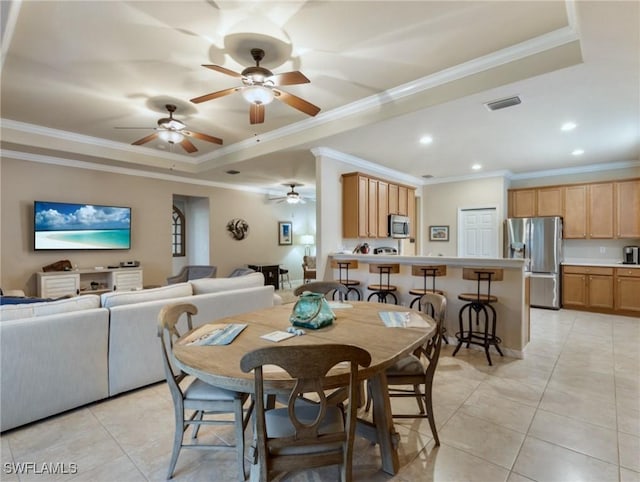 tiled dining space featuring a tray ceiling and ornamental molding