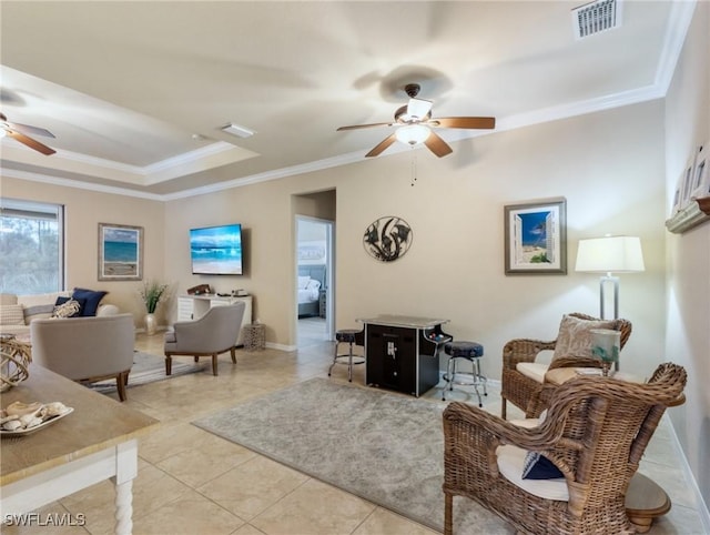 living room with ceiling fan, light tile patterned flooring, ornamental molding, and a tray ceiling