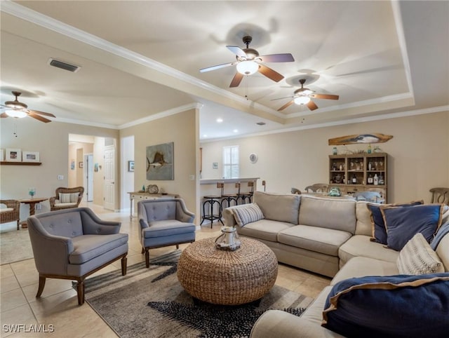 living room featuring light tile patterned flooring, ornamental molding, and a tray ceiling