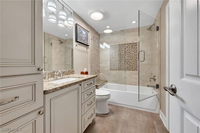 full bathroom with combined bath / shower with glass door, vanity, and toilet