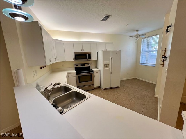 kitchen featuring sink, light tile patterned floors, ceiling fan, appliances with stainless steel finishes, and white cabinets