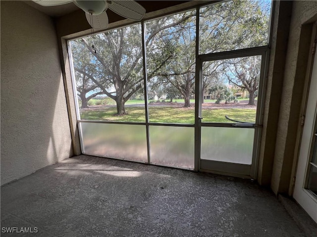 unfurnished sunroom featuring ceiling fan