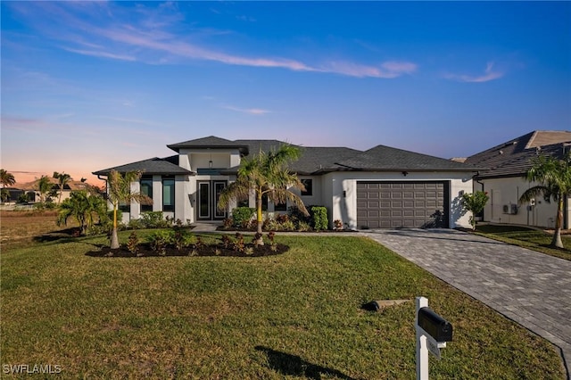 prairie-style home featuring a garage and a lawn