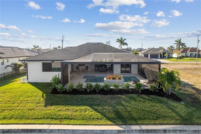 rear view of property featuring a patio, a yard, and glass enclosure