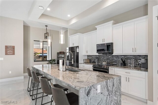 kitchen with white cabinetry, a kitchen island with sink, a kitchen bar, and stainless steel appliances