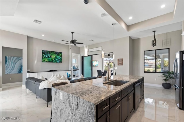 kitchen featuring hanging light fixtures, sink, an island with sink, appliances with stainless steel finishes, and light stone counters