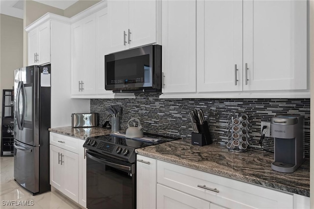 kitchen featuring white cabinetry, black / electric stove, stainless steel refrigerator, and dark stone counters