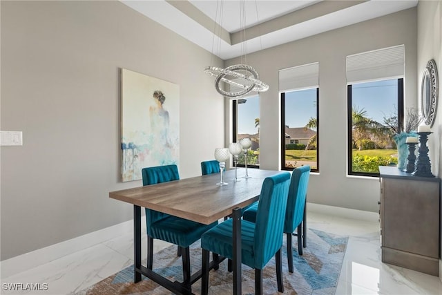 dining space featuring a raised ceiling, a wealth of natural light, and a notable chandelier