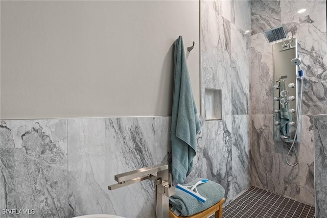 bathroom with tile patterned flooring, a tile shower, and tile walls