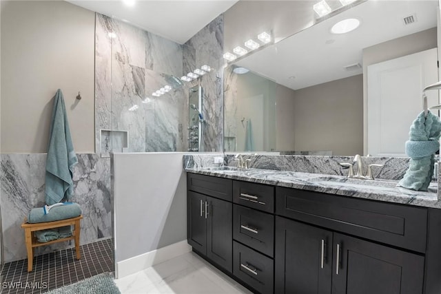 bathroom with tiled shower, vanity, and tile walls