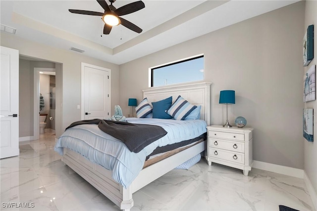 bedroom with a raised ceiling, ceiling fan, and ensuite bathroom