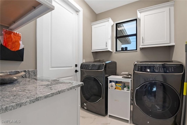 laundry room featuring washing machine and clothes dryer and cabinets