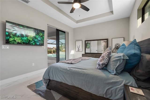 bedroom with ceiling fan, access to exterior, and a tray ceiling