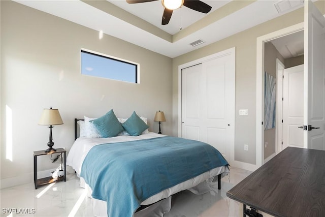 bedroom with a tray ceiling, ceiling fan, and a closet