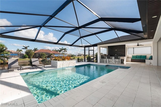 view of swimming pool with glass enclosure, ceiling fan, a bar, and a patio