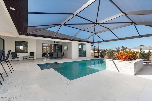 view of swimming pool featuring glass enclosure, ceiling fan, and a patio area