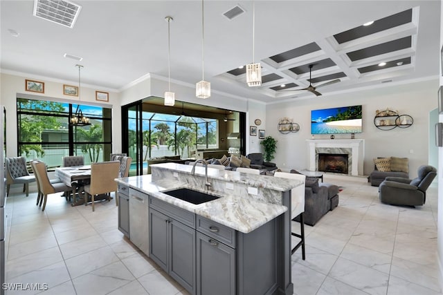 kitchen with hanging light fixtures, gray cabinetry, sink, ceiling fan, and light stone counters