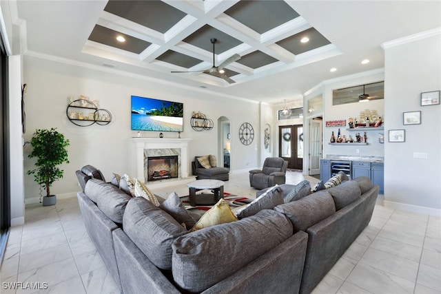 living room featuring indoor bar, beamed ceiling, a fireplace, coffered ceiling, and ornamental molding