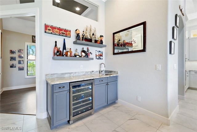 bar featuring sink, blue cabinetry, and beverage cooler