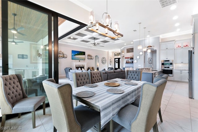 tiled dining area featuring ceiling fan with notable chandelier, sink, and crown molding