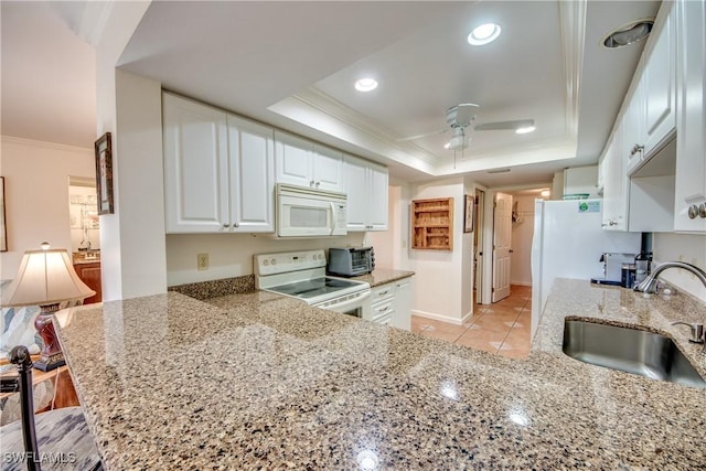 kitchen with kitchen peninsula, white appliances, a raised ceiling, sink, and white cabinets