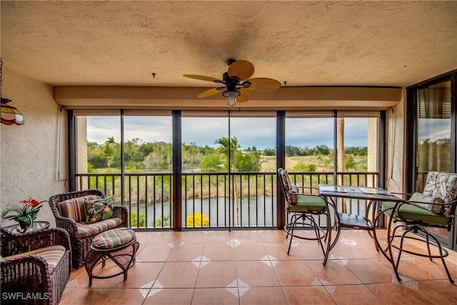 sunroom with a water view and ceiling fan