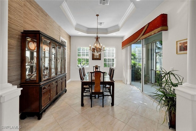 dining room featuring ornate columns, an inviting chandelier, a raised ceiling, light tile patterned floors, and ornamental molding