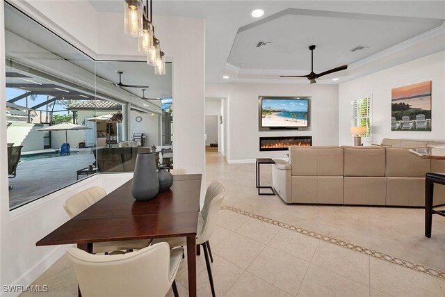 dining area with ceiling fan, light tile patterned floors, crown molding, and a tray ceiling