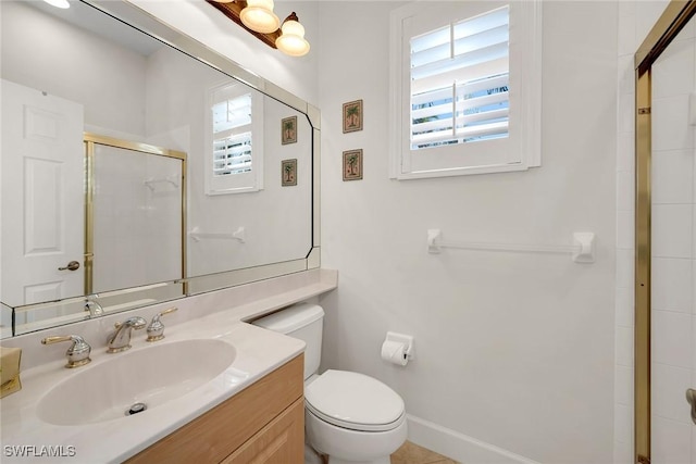 bathroom featuring vanity, toilet, a shower with shower door, and a wealth of natural light