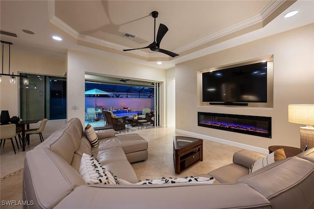 living room featuring ceiling fan, ornamental molding, a tray ceiling, and tile patterned floors