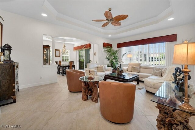 tiled living room featuring a tray ceiling, ceiling fan, and crown molding