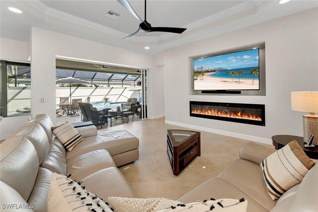 living room featuring a raised ceiling, ceiling fan, and crown molding