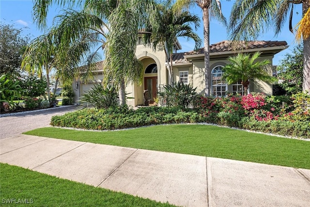 mediterranean / spanish-style home featuring a garage and a front lawn