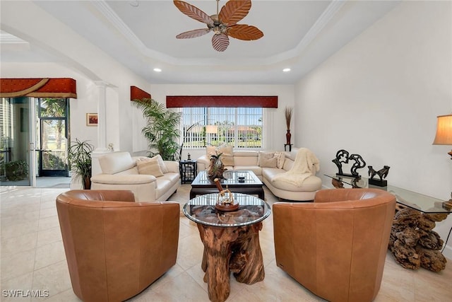 tiled living room featuring decorative columns, a raised ceiling, crown molding, and ceiling fan